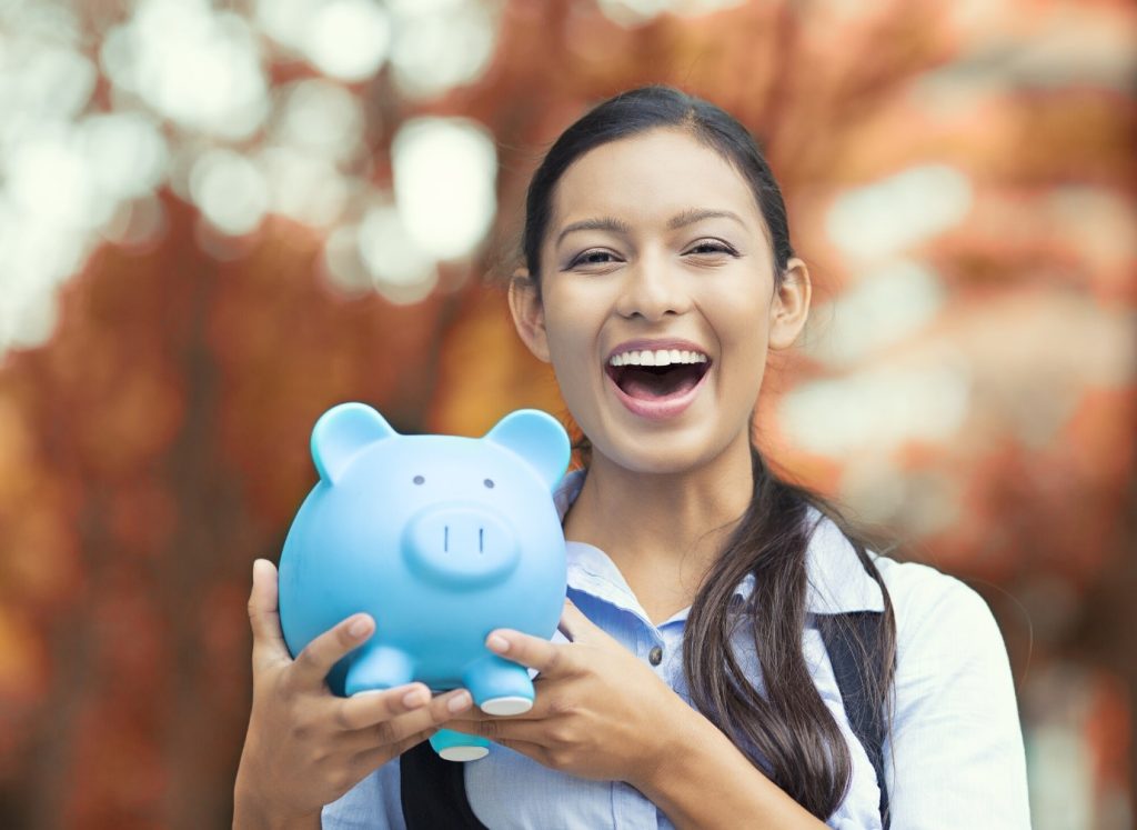 a lady smiling and holding a piggy bank