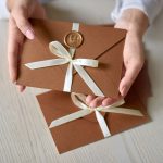 Gift Certificate, gift voucher or discount in woman hand. close-up photo of invitation envelope with ribbon and wax seal, gift certificate, wedding invitation card