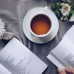 A person reading a book from a branded mug from cuppa kindness