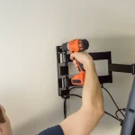 A worker mounting their tv onto the wall
